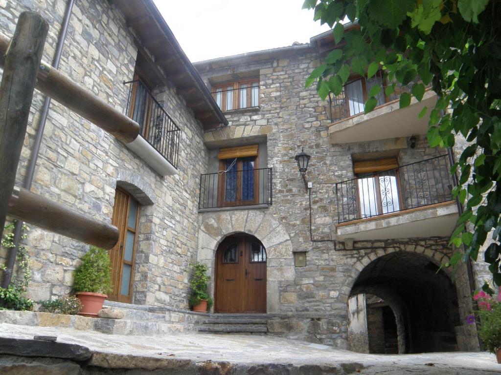 un edificio de piedra con puerta de madera y balcón en Casa Cosculluela, en Aínsa