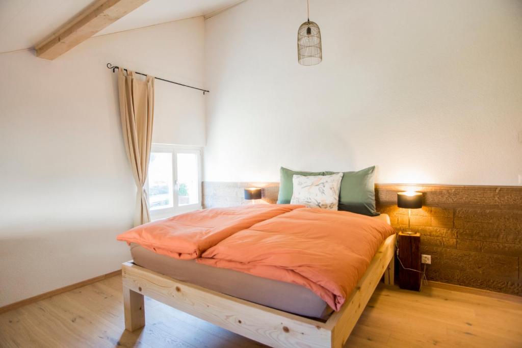 a bedroom with a bed with an orange comforter at BnB Logis des Saules in Saint-Ursanne