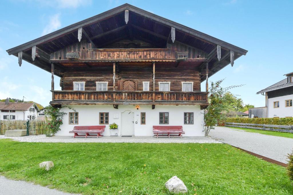 a large wooden building with two benches in front of it at Ferienwohnung Sunnseitn Alte Gendarmerie Übersee in Übersee