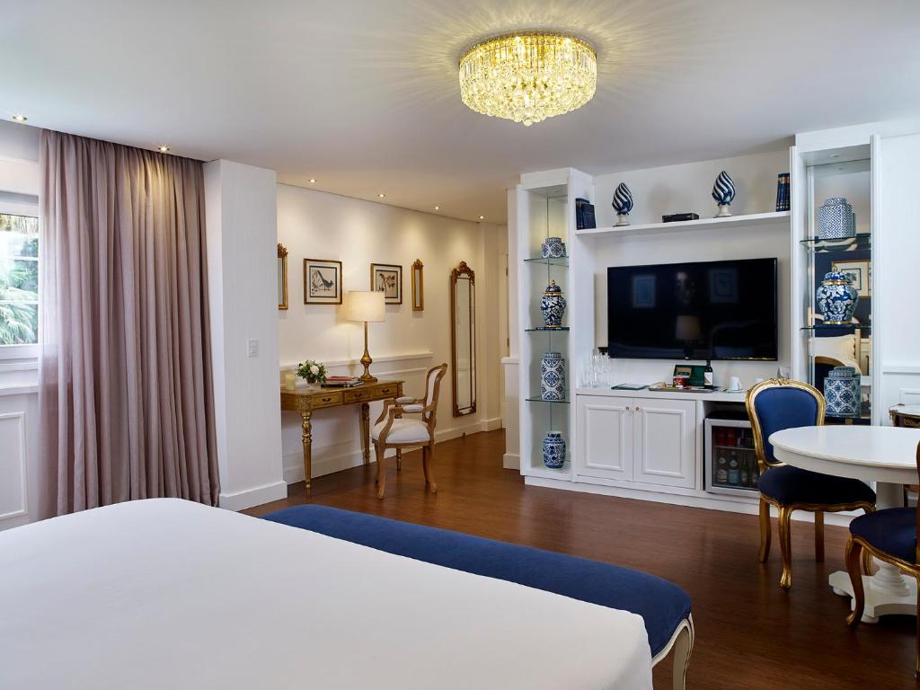 a bedroom with a bed and a table and a tv at Villa do Vale Boutique Hotel in Blumenau
