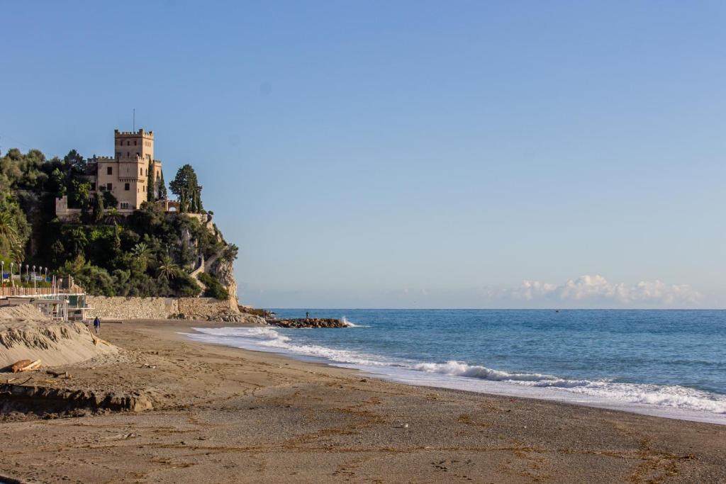 una playa con un edificio en una colina junto al océano en Il molo, en Finale Ligure