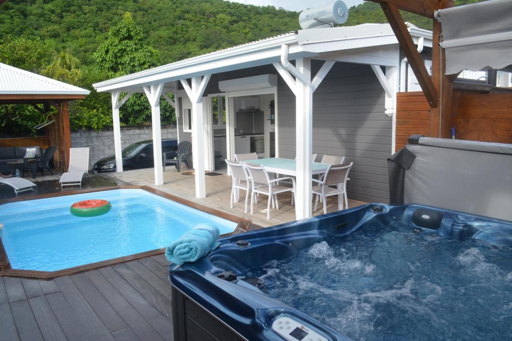 a hot tub on a deck next to a house at Les Lodges de Malendure in Bouillante