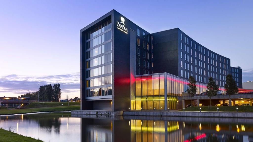 een gebouw met een reflectie in een waterlichaam bij Park Plaza Amsterdam Airport in Lijnden