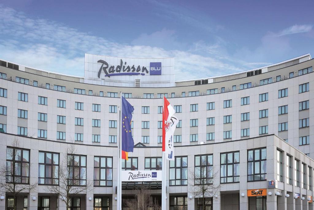 un edificio con dos banderas delante en Radisson Blu Hotel Cottbus en Cottbus