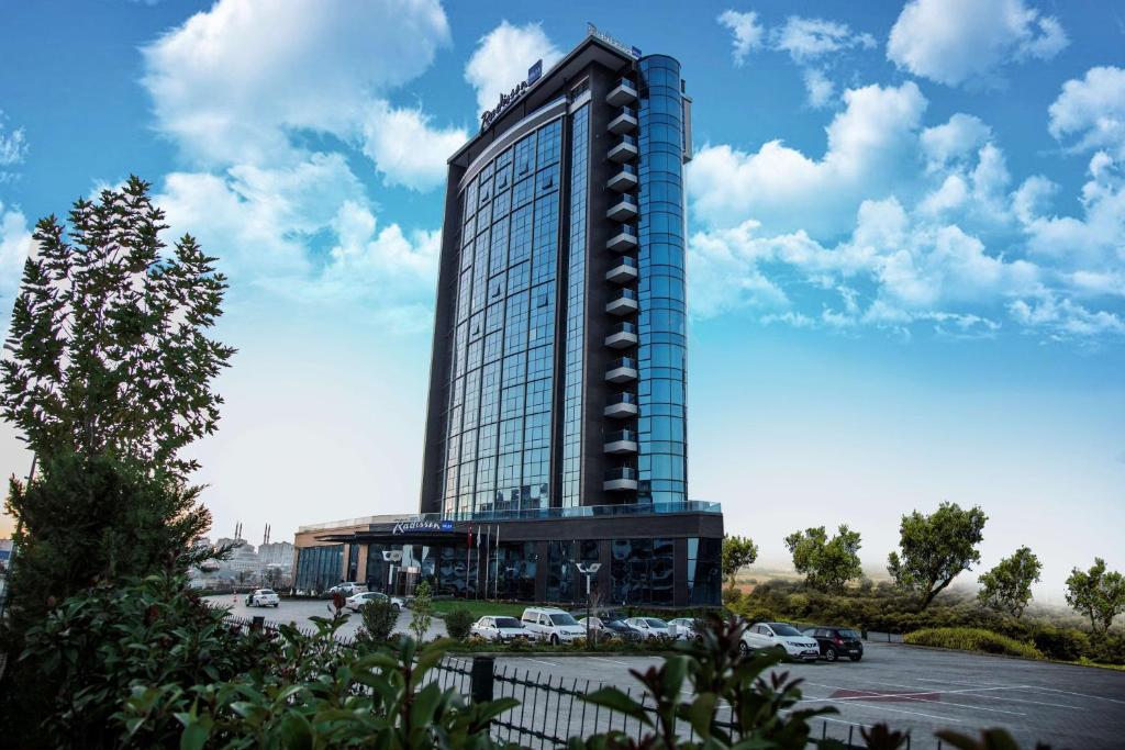un edificio alto con un estacionamiento delante de él en Radisson Blu Hotel, Diyarbakir en Diyarbakir