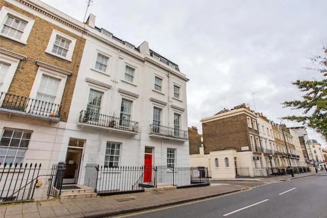 a white building with a red door on a street at Enrico Hotel in London