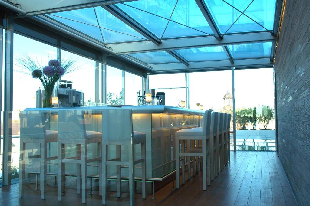 a bar with white chairs in a room with windows at Hotel Bayerischer Hof in Munich