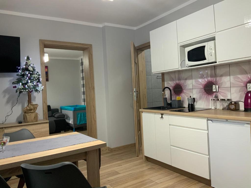 a kitchen with white cabinets and a table and a microwave at Domek na Wzgórzu in Muszyna