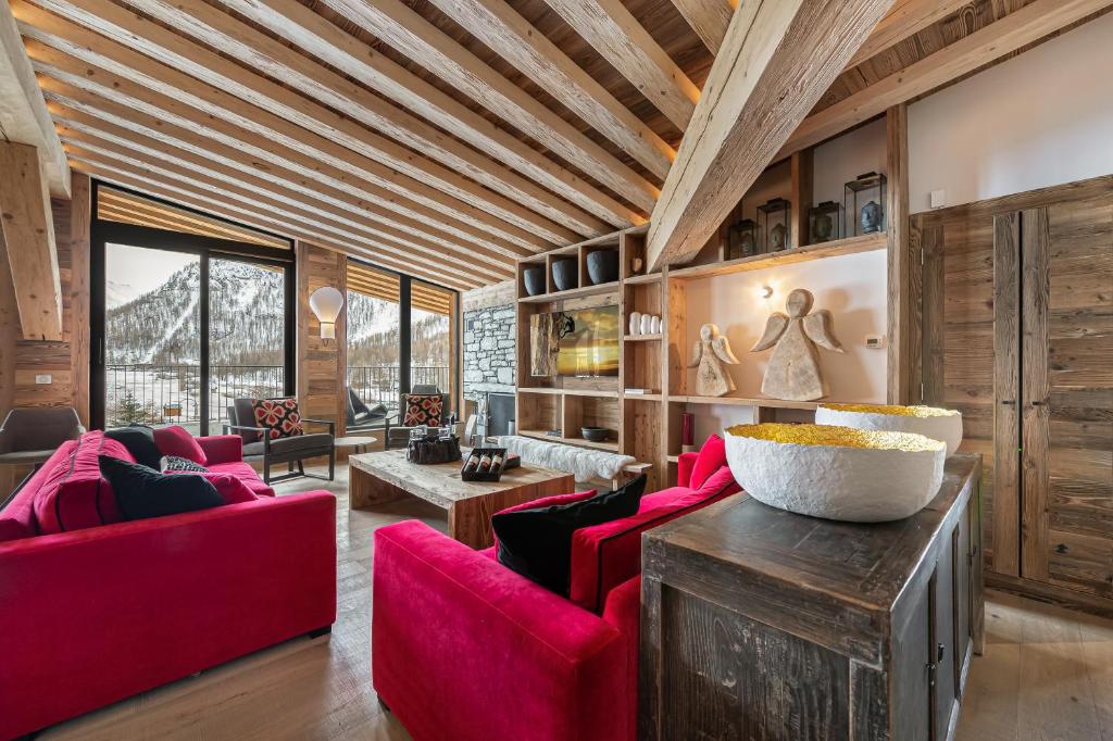 a living room with red furniture and a wooden ceiling at Penthouse Chamois - LES CHALETS COVAREL in La Daille