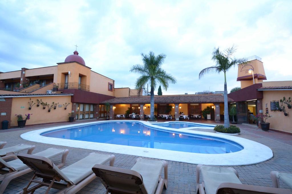 Hotel Hacienda في مدينة أواكساكا: مسبح امام مبنى فيه كراسي ومنتجع