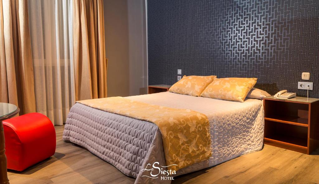 a bedroom with a bed and a red chair at La Siesta in Villamarciel