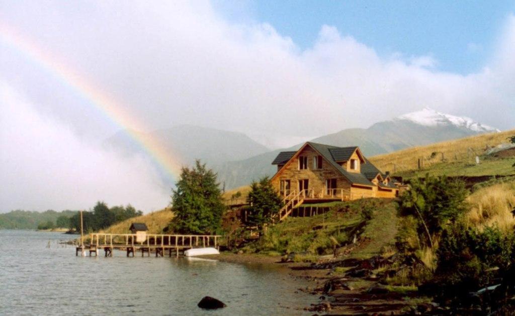 einen Regenbogen vor einem Haus auf einem See in der Unterkunft Lodge de Montaña Lago Monreal in El Blanco