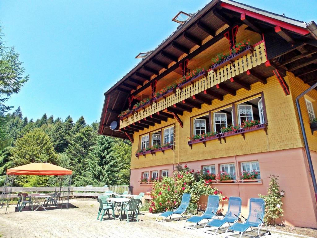 a building with chairs and a table and an umbrella at Ferienwohnung mit Talblick in Todtmoos in Todtmoos