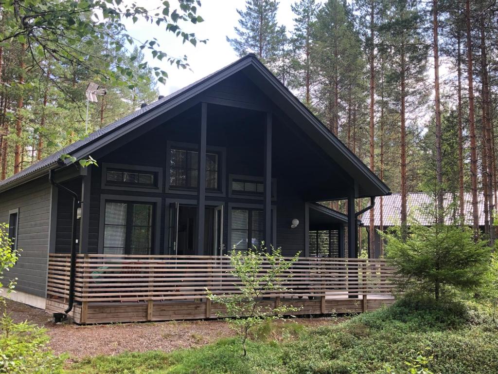 a black cabin with a porch in the woods at Ähtärin lomamökit - AARRE Mökki in Ähtäri