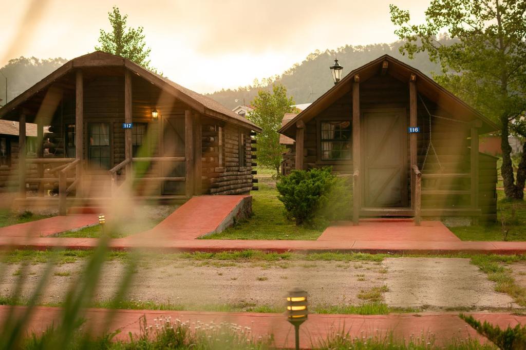 a couple of small wooden buildings with a house at Villa Mexicana Creel Mountain Lodge in Creel