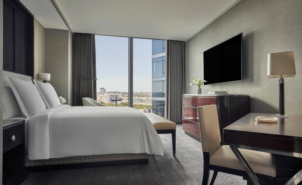 a hotel room with a bed and a desk and a window at Four Seasons Hotel One Dalton Street, Boston in Boston