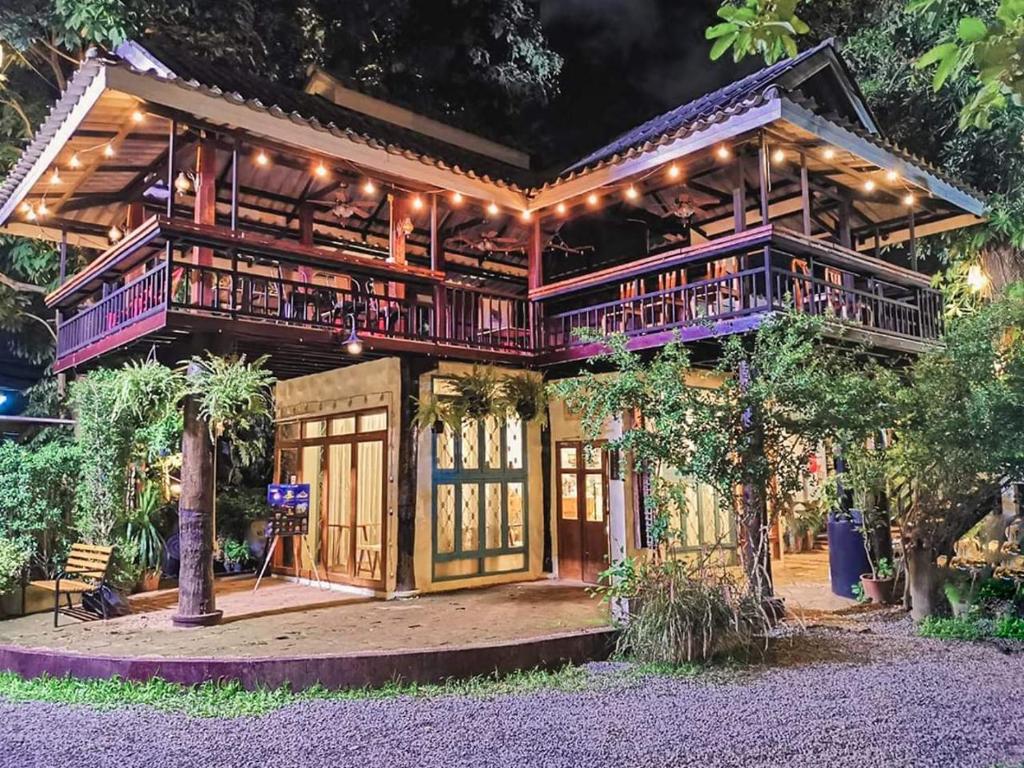 a wooden house with a balcony and lights at Sukjai Guesthouse in Chiang Mai