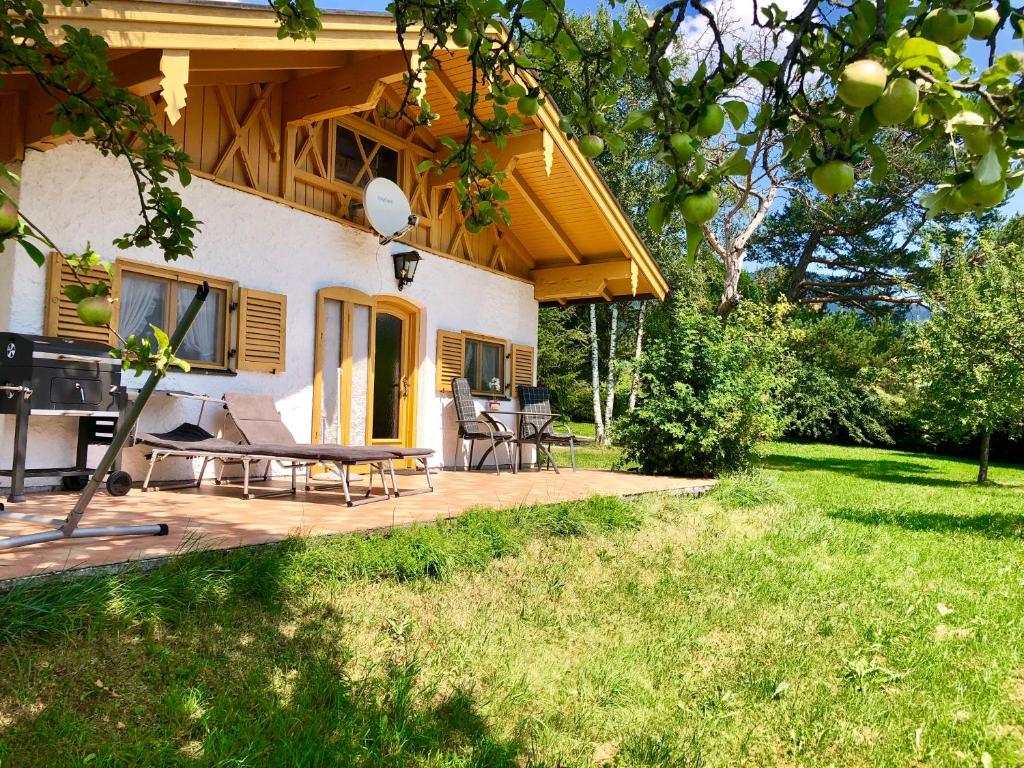 uma casa com uma mesa de piquenique e cadeiras num deque em Ferienhaus Veronika mit 2000qm Garten und Bergblick em Unterammergau