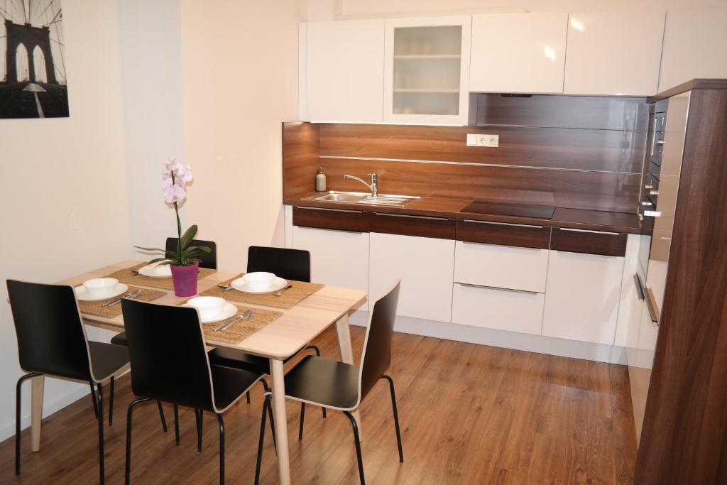 cocina con mesa, sillas y fregadero en Riverside Apartman with Free Parking en Győr