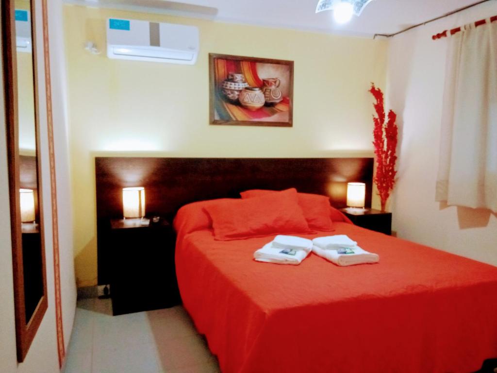 a bedroom with a red bed with two towels on it at Departamento Arenas in Maipú
