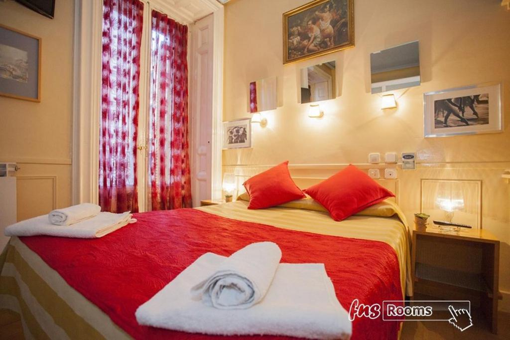 a bedroom with a red bed with towels on it at Hostal La Fontana in Madrid