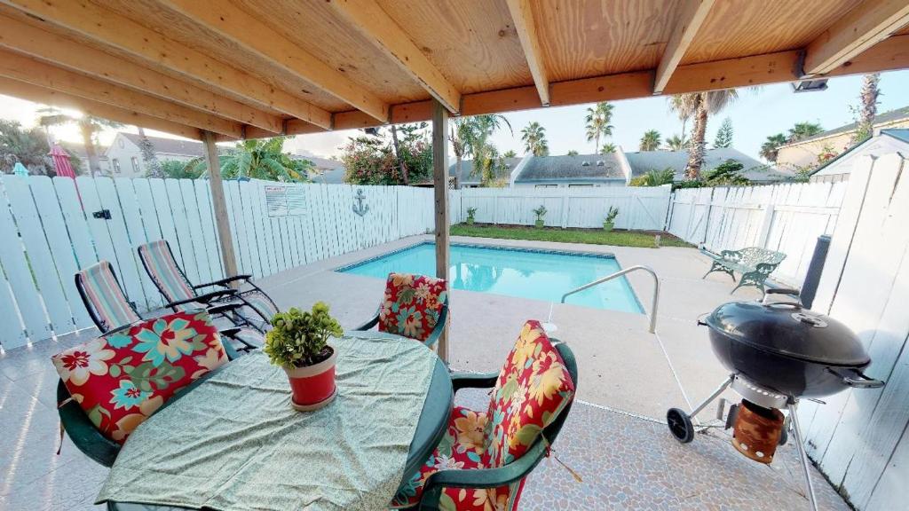 a patio with a table and chairs and a grill at Padre Pool House townhouse in South Padre Island