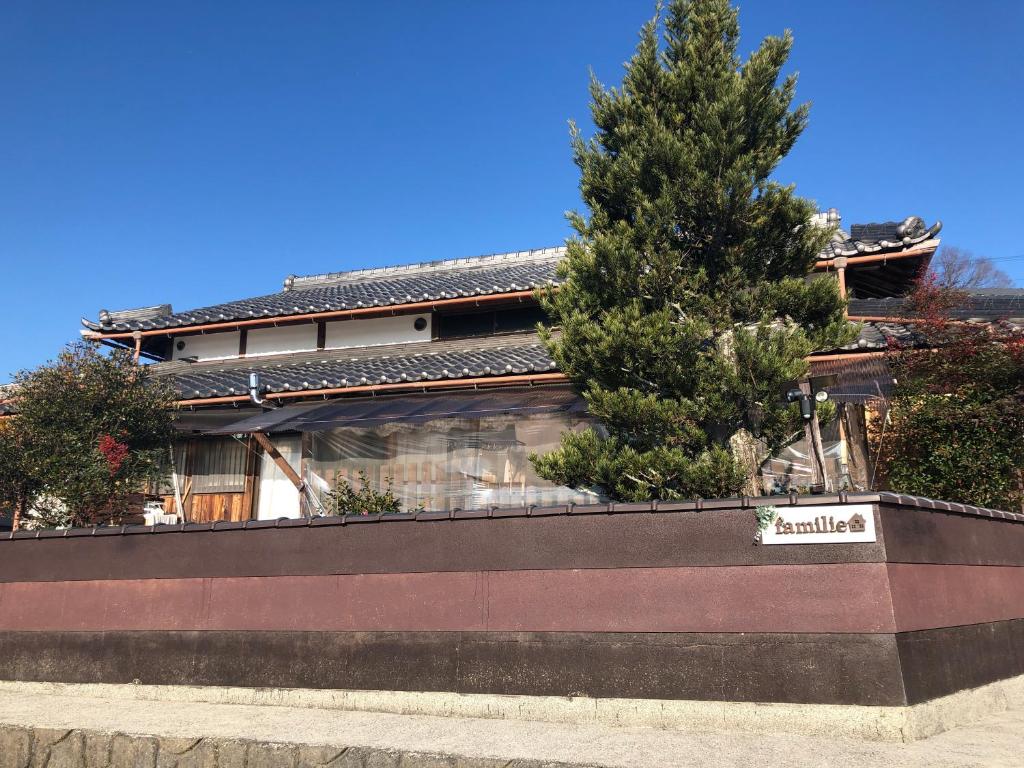 una casa con un árbol delante de ella en familie en Otsu