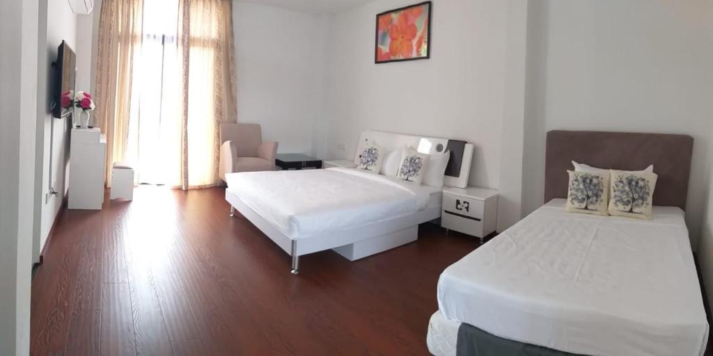 a white bedroom with two beds and a couch at Coconut Bay Lodge in Bandar Seri Begawan