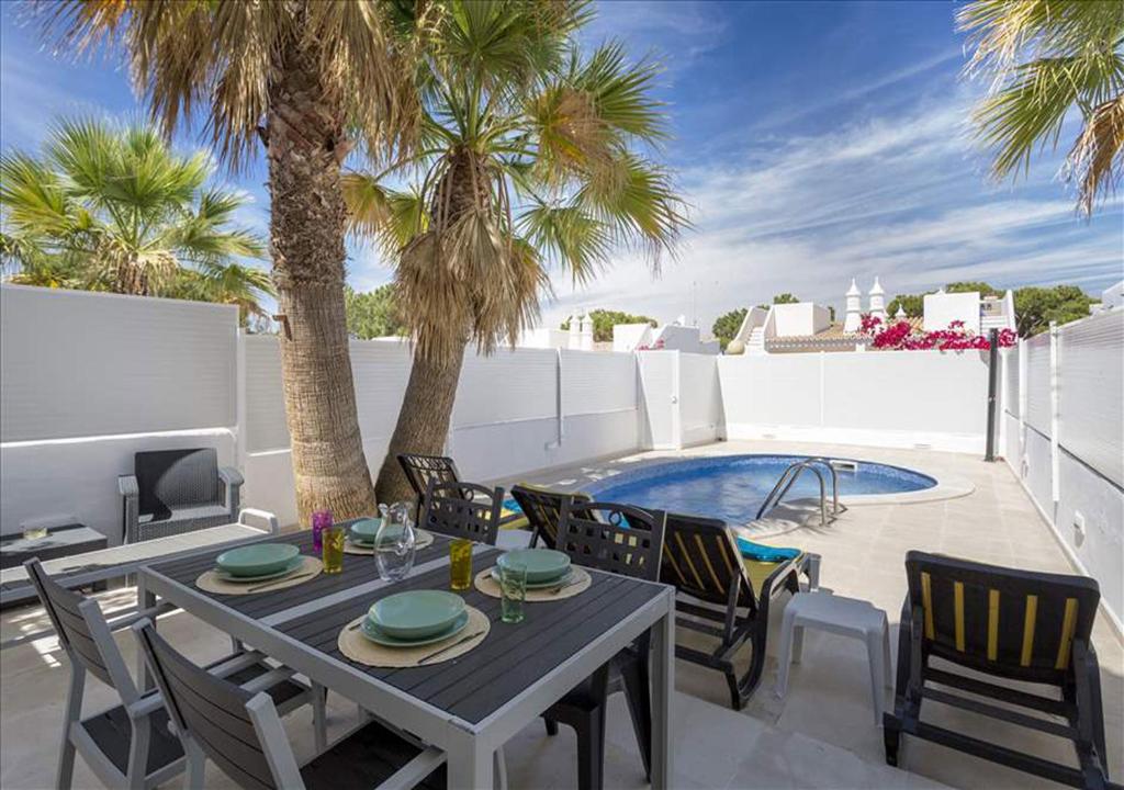 a patio with a table and chairs and a pool at Vicky Rae Beach House - Vale do Lobo in Almancil