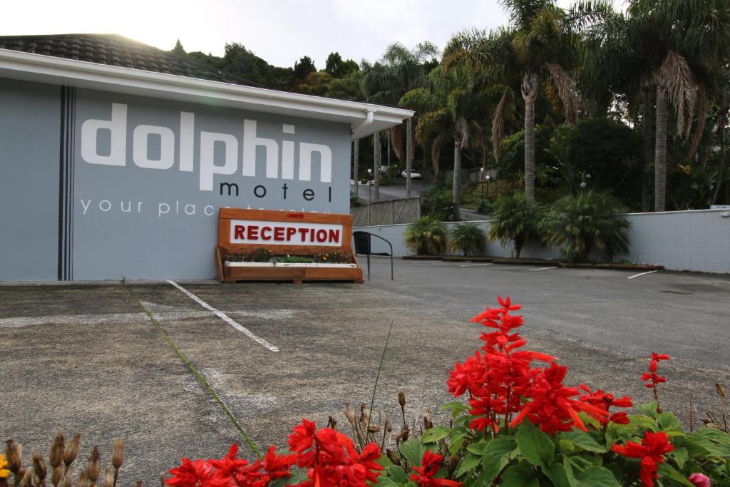 un panneau devant un parking avec des fleurs rouges dans l'établissement Dolphin Motel, à Paihia