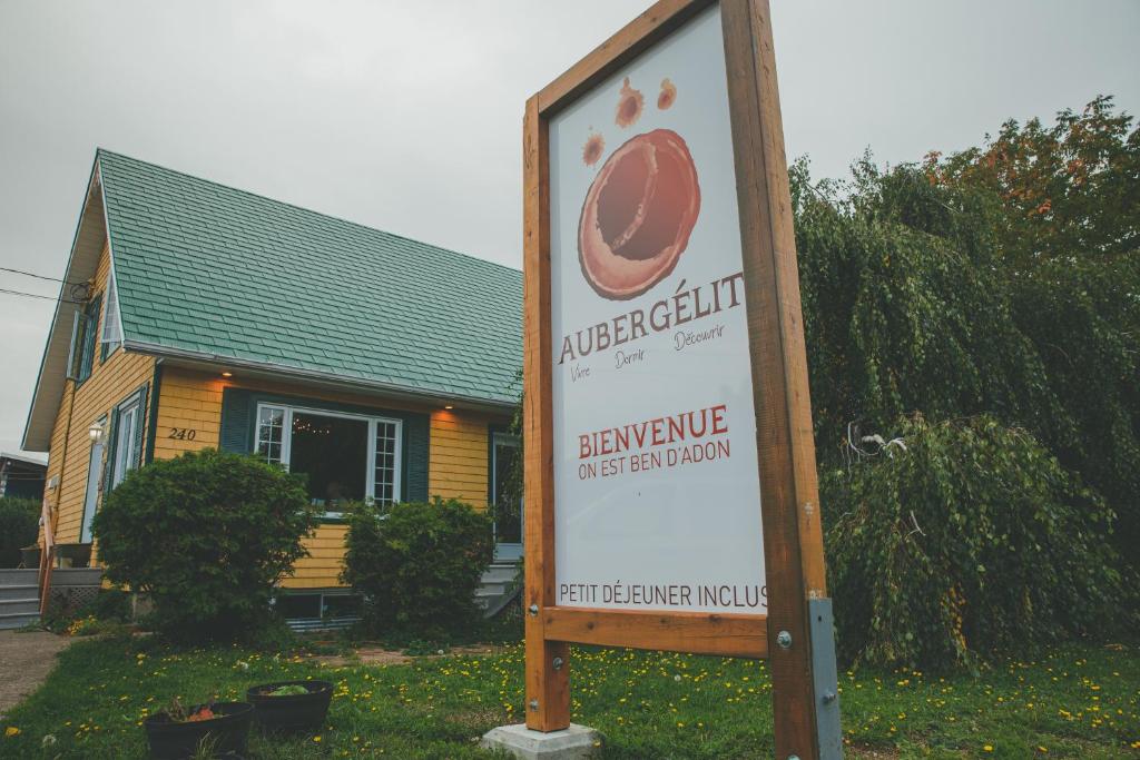 a sign in front of a house with a building at Gîte B&B - Aubergélit inc in Saint-Jean-Port-Joli