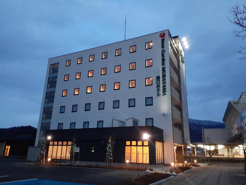 een groot wit gebouw met lichten ervoor bij Murayama Nishiguchi Hotel in Murayama