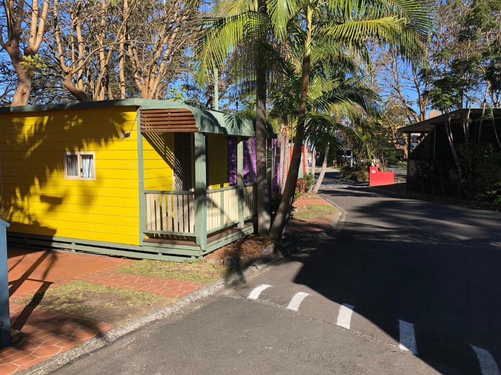 una casa amarilla al lado de una calle en Palm Beach Caravan Park en Sanctuary Point
