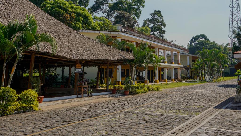a building with a straw roof on a cobblestone street at Zafra Hotel in Ceiba Blanca