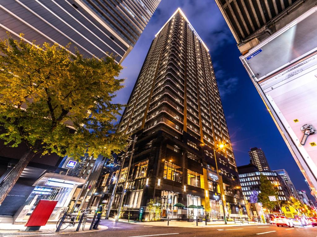 een hoog gebouw in de stad 's nachts bij APA Hotel & Resort Midosuji Hommachi Eki Tower in Osaka