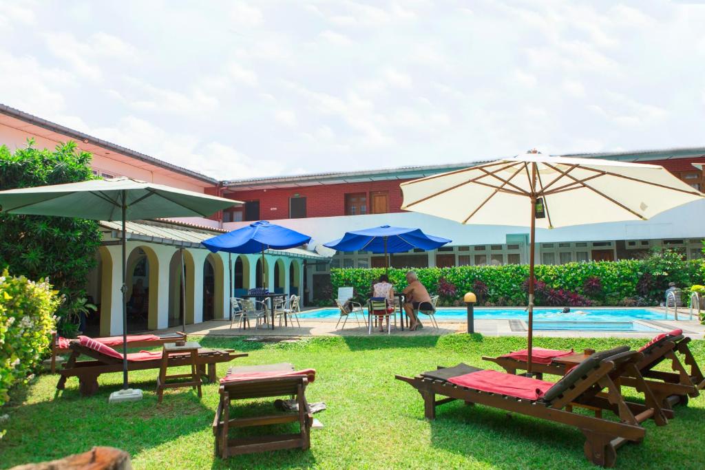 un patio con mesas, sombrillas y una piscina en Ranveli Beach Resort en Mount Lavinia