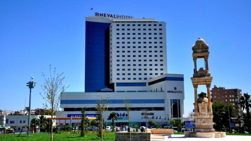 un grand bâtiment bleu avec une statue en face dans l'établissement NEVALI HOTEL, à Şanlıurfa