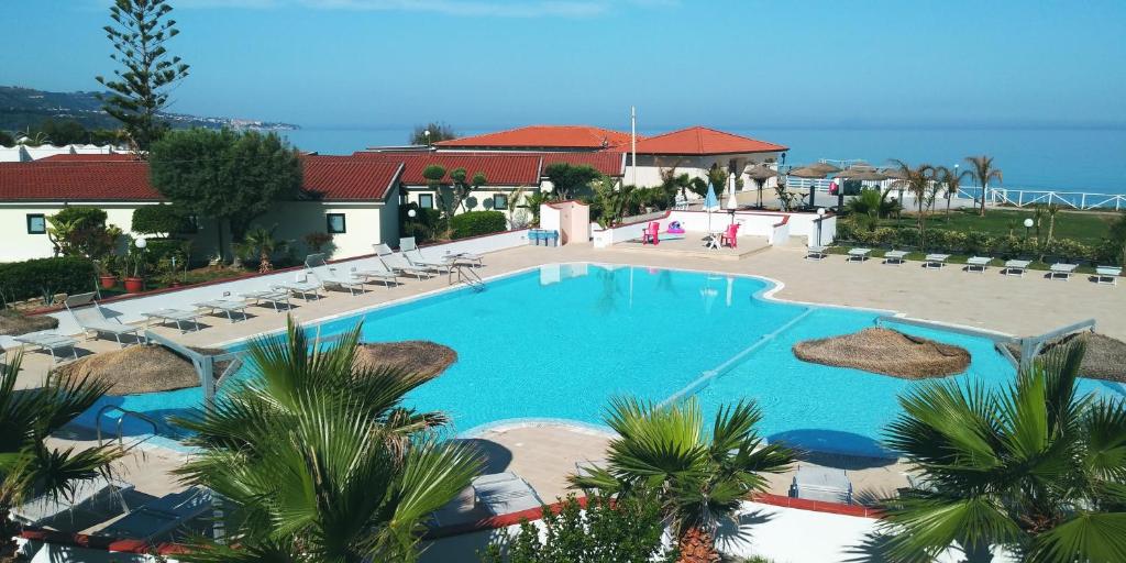 einen großen Pool mit Palmen und dem Meer in der Unterkunft Borgo Marino Albatros in Zambrone