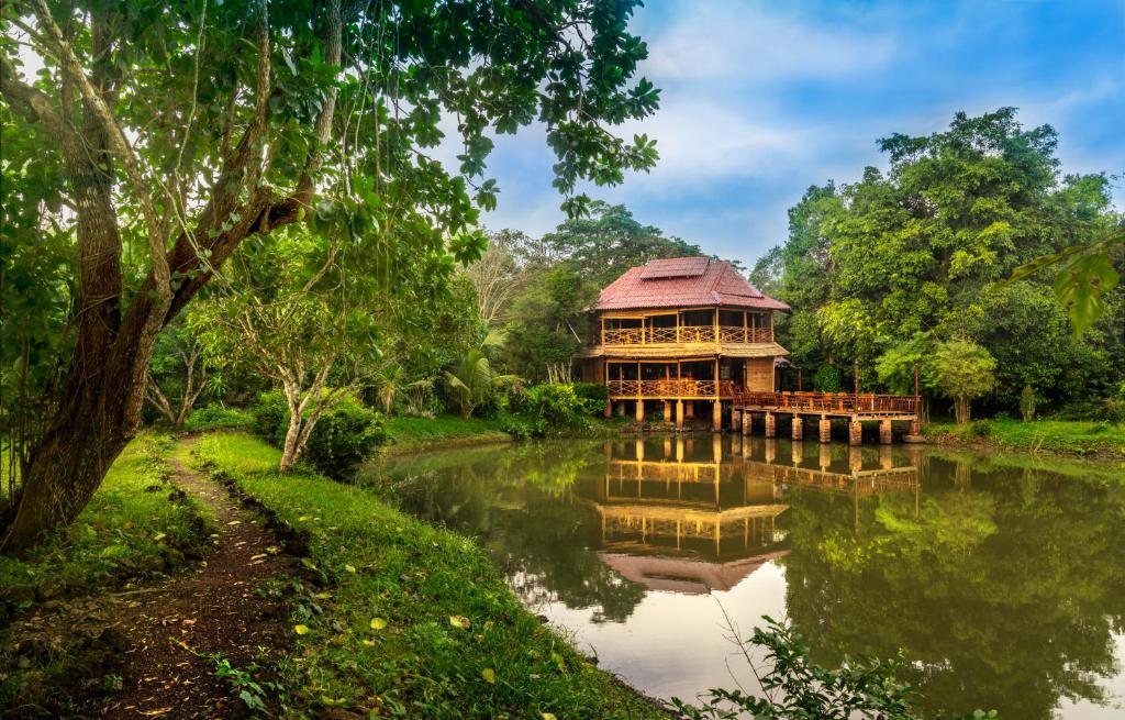 un grand bâtiment en bois sur une rivière arborée dans l'établissement Kingfisher Ecolodge, à Ban Kian-Ngông
