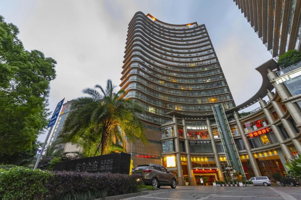 un edificio alto con una palmera delante de él en East King Business Hotel (West Lake store, Hangzhou) en Hangzhou
