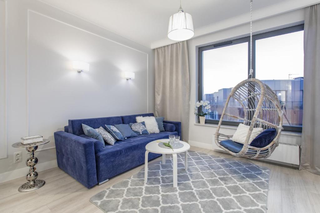 un soggiorno con divano blu e altalena di Lion Apartments - NaviFlat Brabank Premium Apartment with parking a Danzica