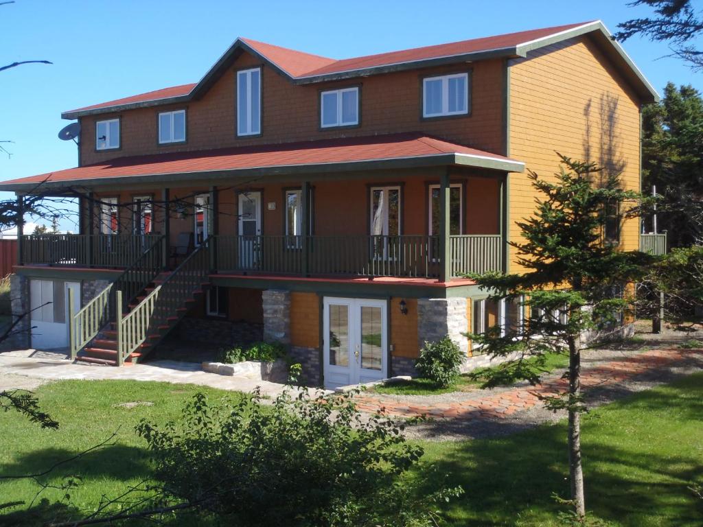 a large house with a porch and a balcony at Gîte La Maison Chez J.P. Bed and Breakfast in Havre aux Maisons