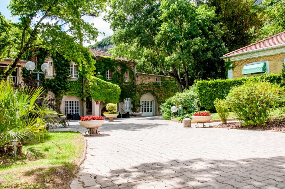 a stone courtyard with two benches in front of a house at Le Cèdre de Soyons in Soyons