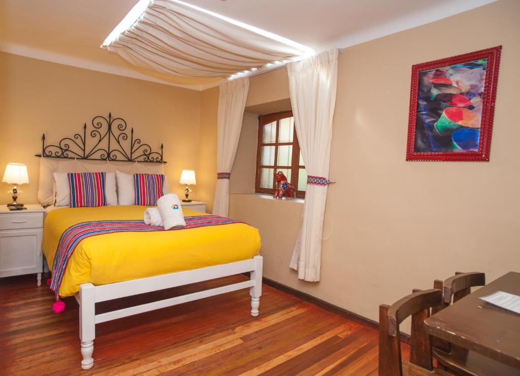 Un dormitorio con una cama amarilla y una mesa en Casa Saphi, en Cusco