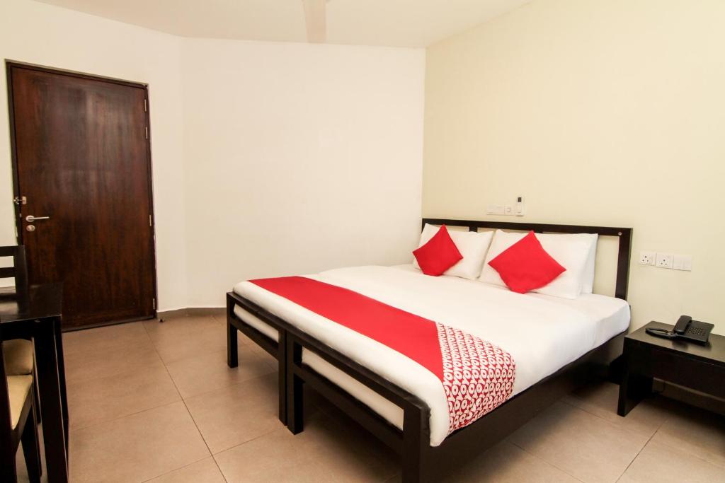 um quarto com uma cama com almofadas vermelhas e brancas em Saninro Hotel - Ragama em Ragama