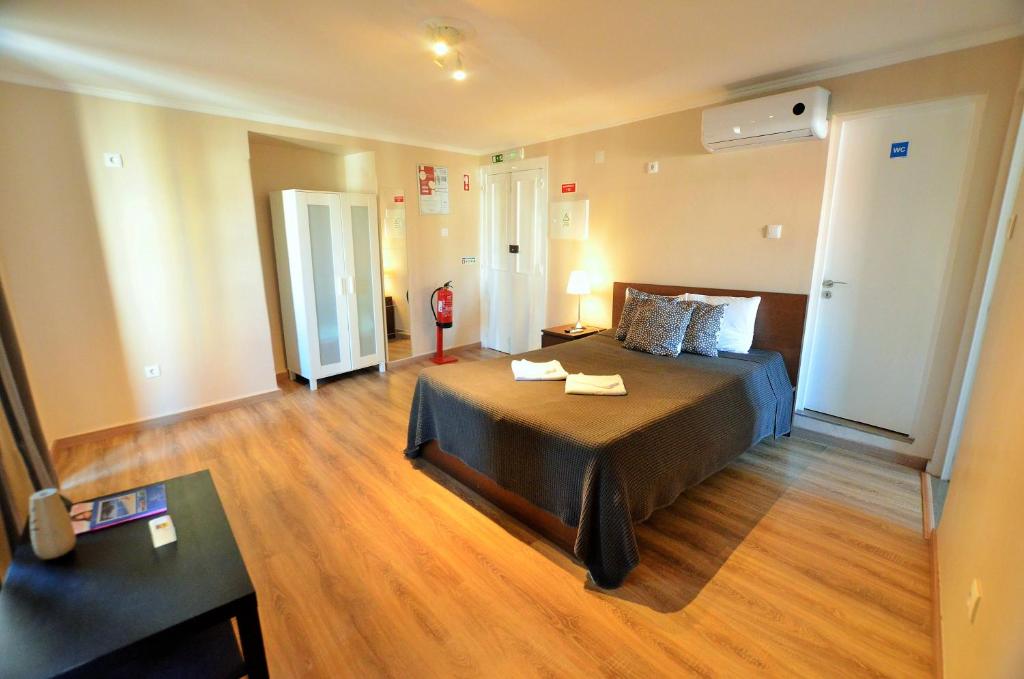 a bedroom with a large bed and a wooden floor at Suites & Apartments - DP Setubal in Setúbal