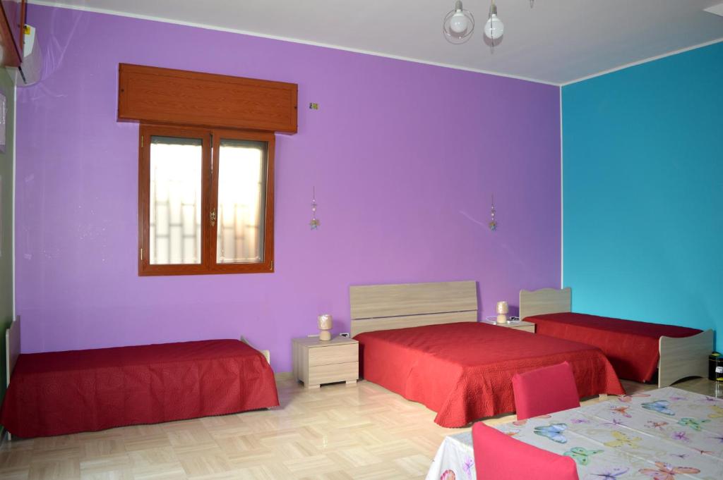 Dormitorio púrpura con 2 camas y ventana en Rooms131, en Margherita di Savoia