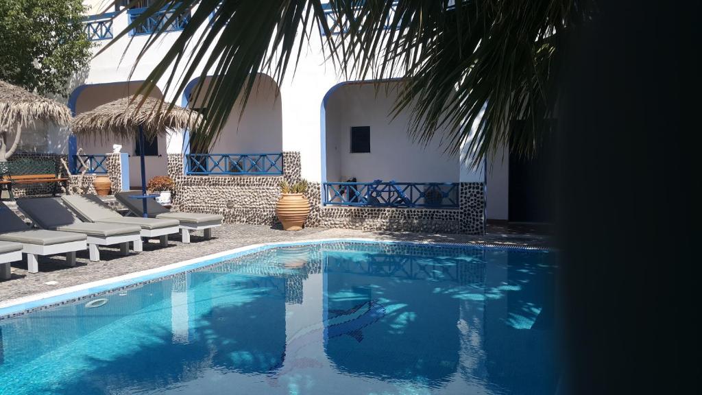 a swimming pool with blue water in front of a house at DARZENTA ATHINA APARTMENTS Perissa in Perissa