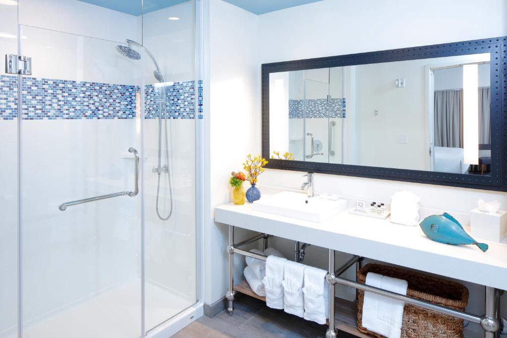 a bathroom with a sink and a shower and a mirror at Hotel Indigo Orange Beach - Gulf Shores by IHG in Gulf Shores