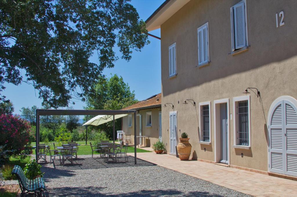 a patio with tables and chairs next to a building at Agriturismo Poderedodici in Orbetello